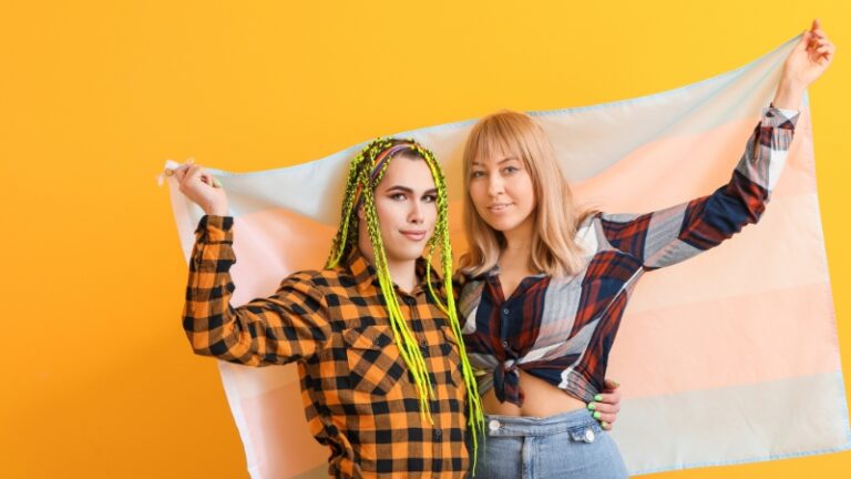 The image shows two people holding a flag, representing transmasculine vs. nonbinary