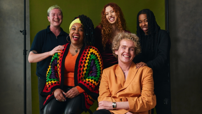 A diverse group of queer people smile together, representing the future of inclusive and supportive queer housing in Tucson
