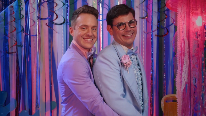 Two men in pastel tuxedos smile and pose together at a colorful dance in a scene from the Netflix series Special