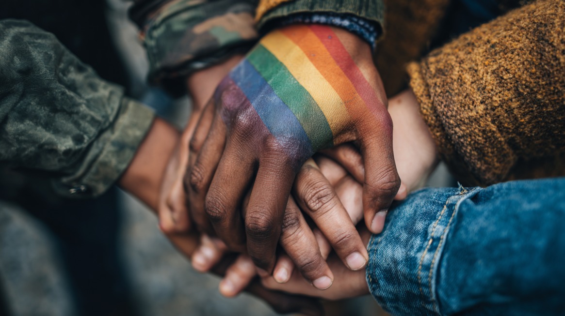 Group of people holding hands with a rainbow pride flag painted on one hand